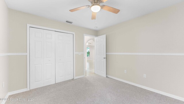 unfurnished bedroom with ceiling fan, a closet, and light carpet