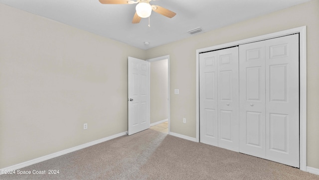 unfurnished bedroom with ceiling fan, light colored carpet, and a closet