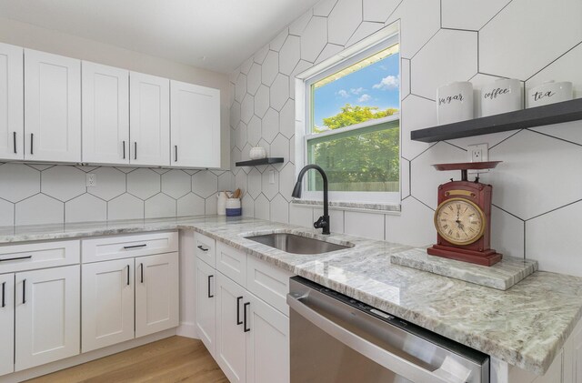 kitchen with tasteful backsplash, sink, dishwashing machine, light hardwood / wood-style floors, and white cabinetry