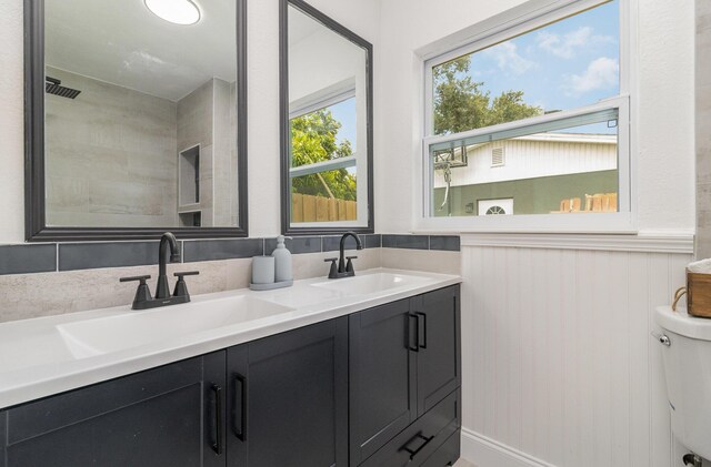 bathroom featuring dual vanity, toilet, and a healthy amount of sunlight