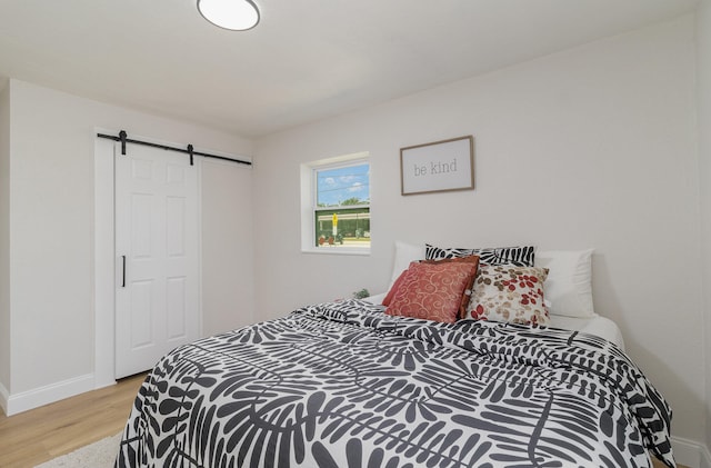 bedroom with light hardwood / wood-style floors and a barn door