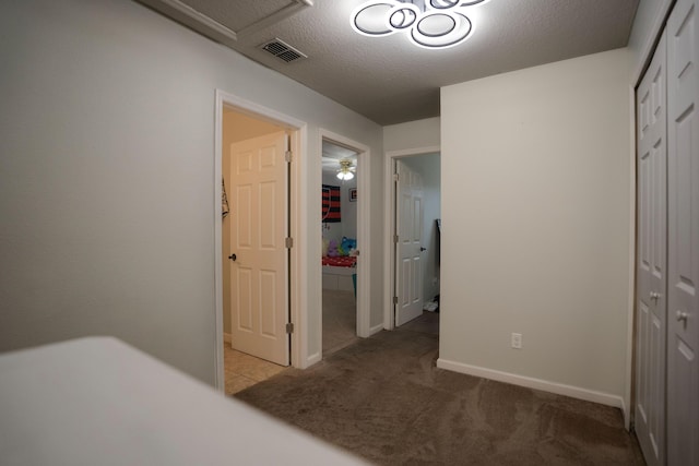 hall with carpet floors and a textured ceiling