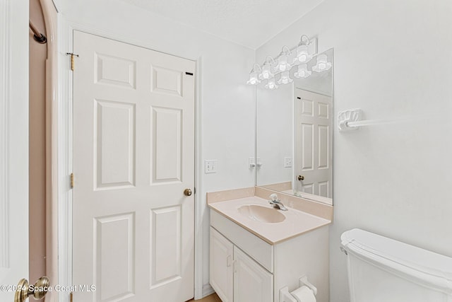 bathroom featuring vanity, a textured ceiling, and toilet