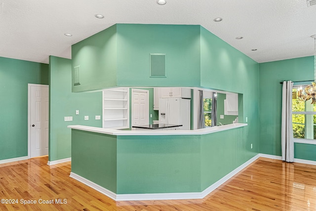 kitchen featuring kitchen peninsula, a healthy amount of sunlight, white refrigerator with ice dispenser, and light wood-type flooring