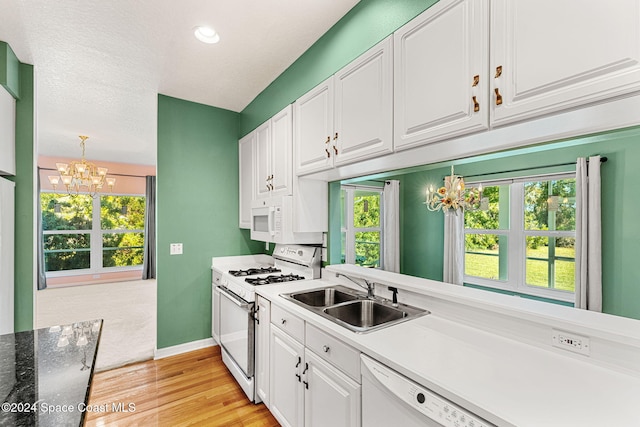 kitchen with white cabinetry, white appliances, sink, and light hardwood / wood-style flooring