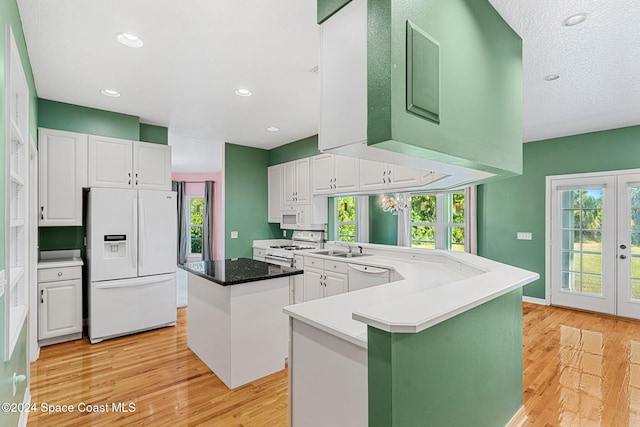 kitchen with white cabinetry, a center island, kitchen peninsula, white appliances, and light wood-type flooring