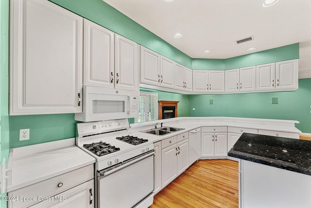 kitchen with white cabinets, light hardwood / wood-style floors, and white appliances