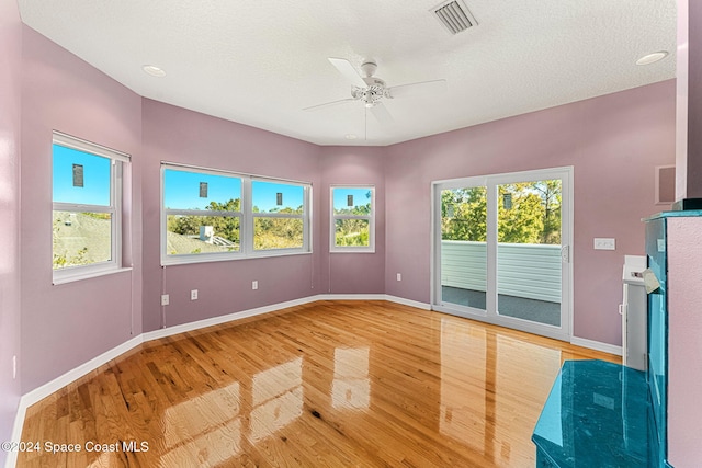 spare room featuring hardwood / wood-style floors, a textured ceiling, ceiling fan, and a healthy amount of sunlight