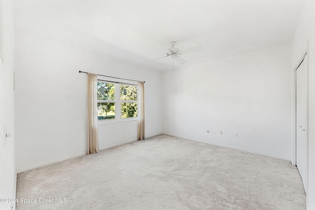 unfurnished room with a textured ceiling, ceiling fan, and light carpet