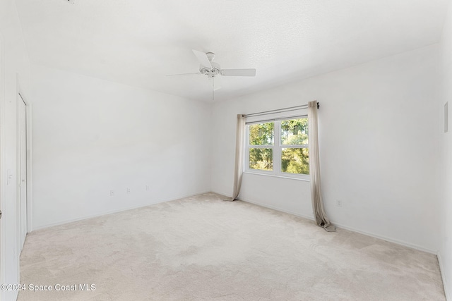 unfurnished room with light colored carpet and ceiling fan