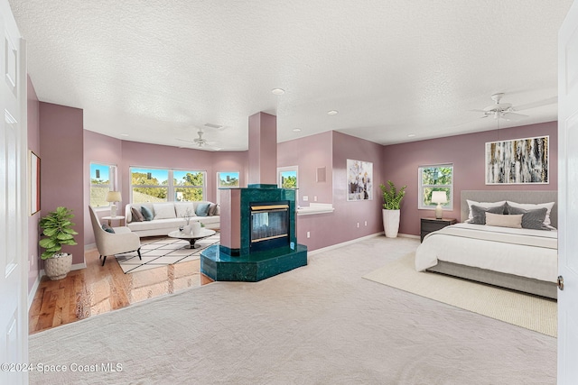 bedroom with ceiling fan, light hardwood / wood-style floors, and a textured ceiling