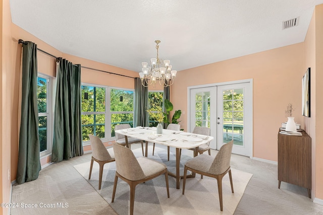 carpeted dining room with a chandelier, french doors, and a textured ceiling