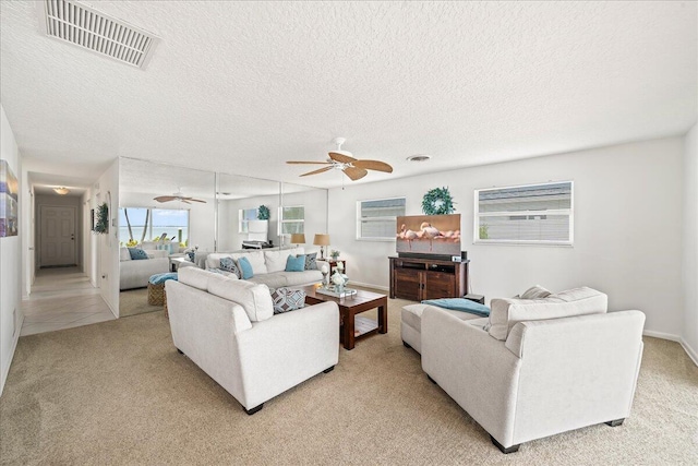 carpeted living room with a textured ceiling and ceiling fan