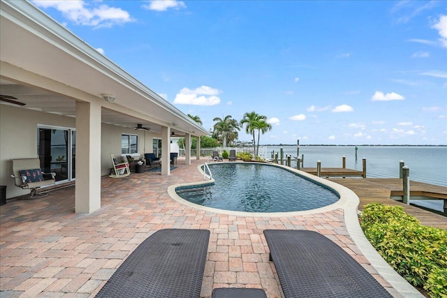 view of pool with a patio area, a dock, ceiling fan, and a water view