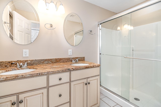 bathroom with a shower with shower door, double vanity, and tile patterned floors