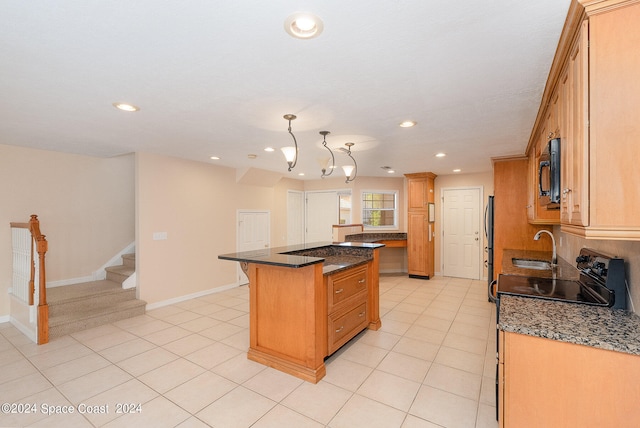 kitchen featuring dark stone countertops, a kitchen island, light tile patterned floors, pendant lighting, and black appliances