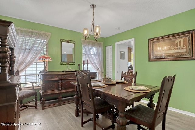 dining area with a notable chandelier, a wealth of natural light, and light hardwood / wood-style floors