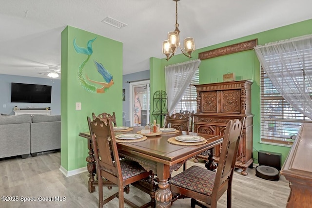 dining space with ceiling fan with notable chandelier and light wood-type flooring