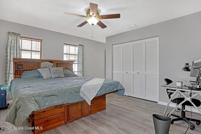 bedroom featuring ceiling fan, light hardwood / wood-style flooring, a closet, and a textured ceiling