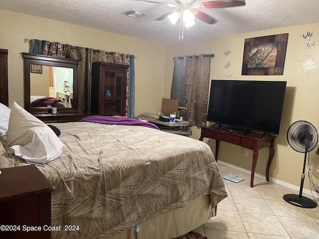 bedroom with ceiling fan, light tile patterned floors, and a textured ceiling