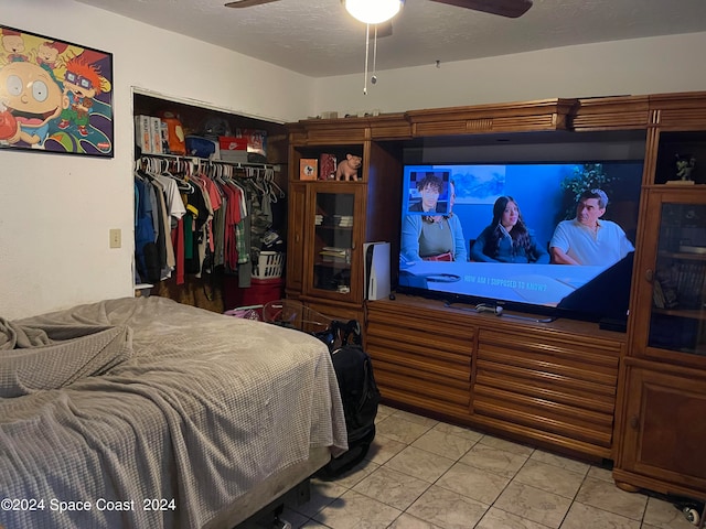 bedroom featuring ceiling fan, light tile patterned floors, a textured ceiling, and a closet