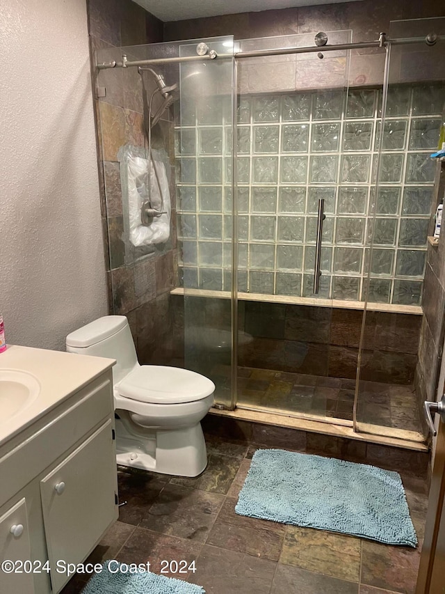 bathroom with walk in shower, vanity, and toilet