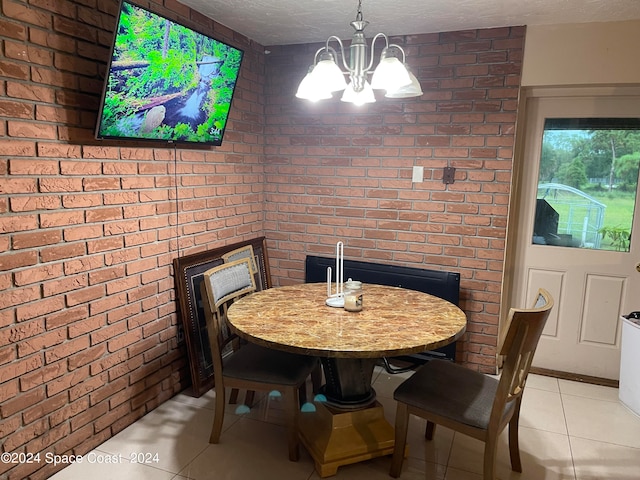 dining space featuring light tile patterned floors, a notable chandelier, and brick wall