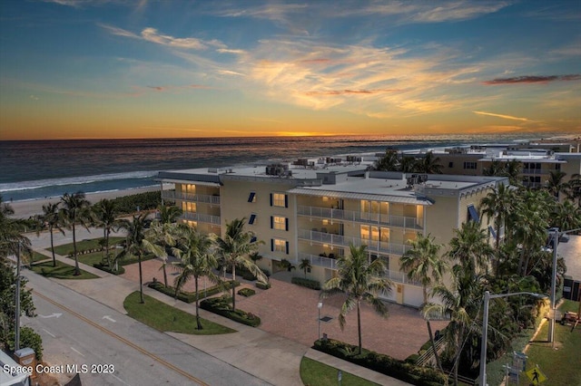 aerial view at dusk with a water view and a beach view