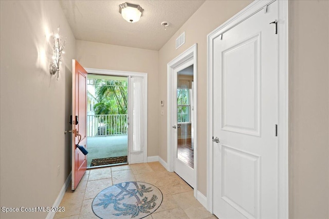 doorway with light tile patterned floors and a textured ceiling