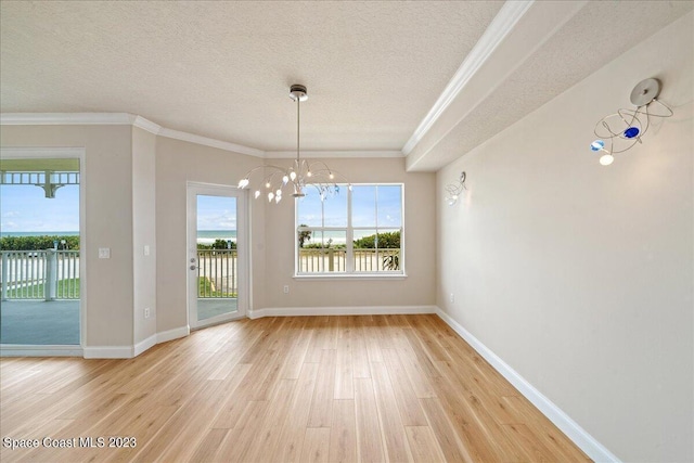 unfurnished dining area with a textured ceiling, an inviting chandelier, ornamental molding, and hardwood / wood-style floors