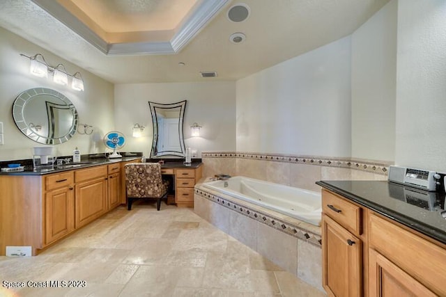 bathroom with a relaxing tiled tub, a tray ceiling, and vanity