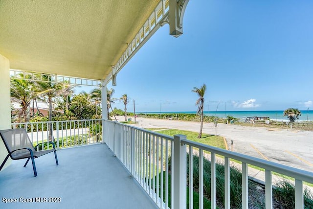 balcony with a water view and a view of the beach