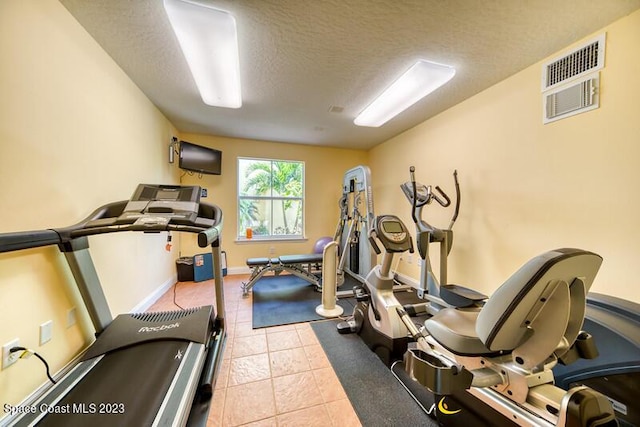 workout area featuring light tile patterned floors and a textured ceiling