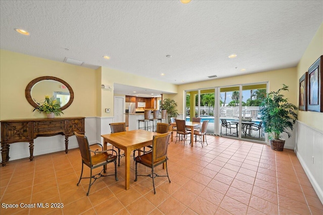 dining space with a textured ceiling and light tile patterned flooring