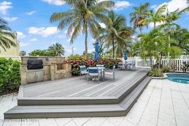 deck with a pool, an outdoor kitchen, and grilling area