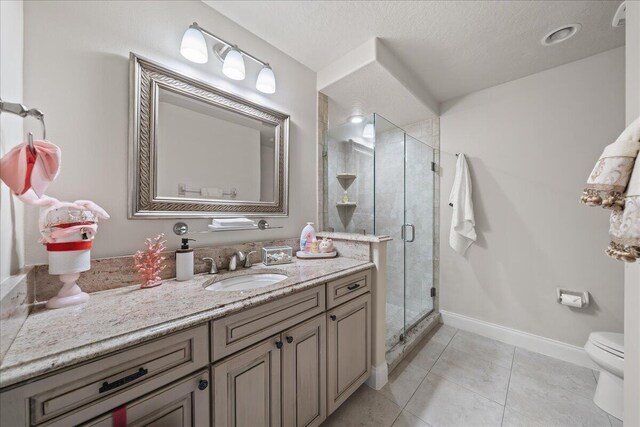 bathroom featuring toilet, tile patterned flooring, walk in shower, a textured ceiling, and vanity