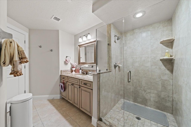 bathroom with toilet, vanity, tile patterned flooring, a textured ceiling, and a shower with door