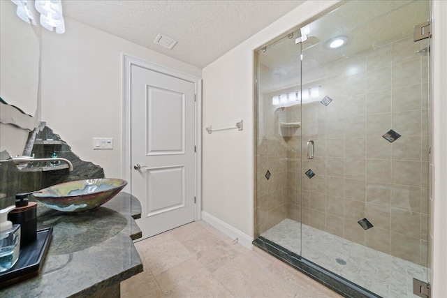 bathroom featuring sink, a textured ceiling, a shower with door, and tile patterned flooring