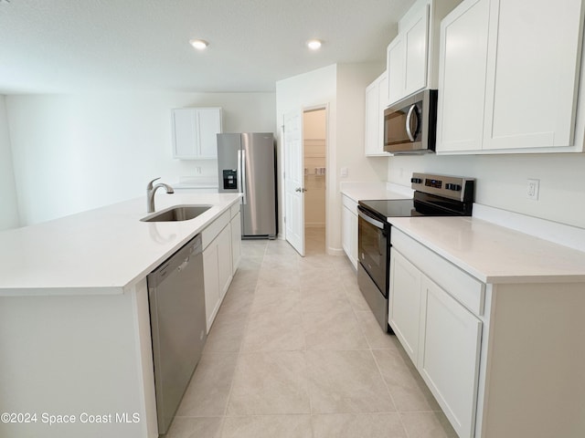 kitchen featuring sink, light tile patterned floors, white cabinetry, stainless steel appliances, and an island with sink