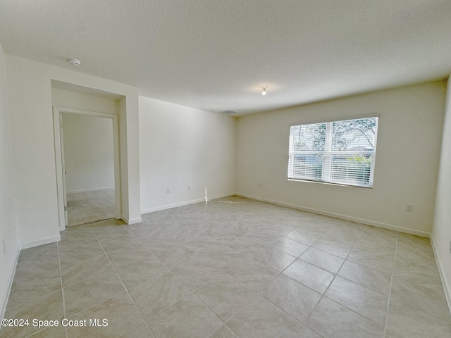 tiled spare room featuring a textured ceiling