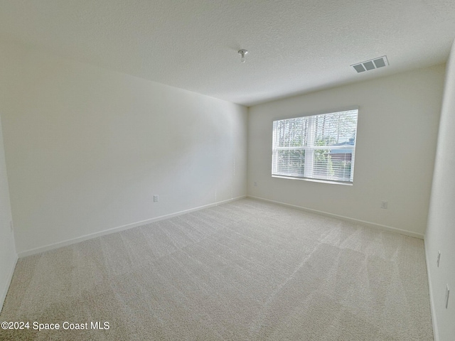 empty room featuring light carpet and a textured ceiling