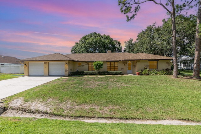 ranch-style home with a garage and a yard