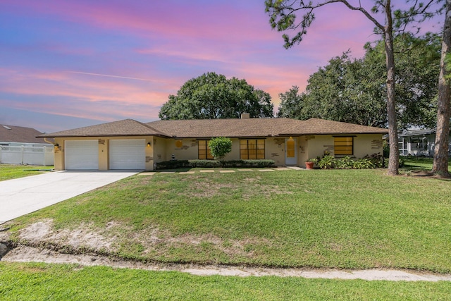 ranch-style house featuring a garage and a lawn