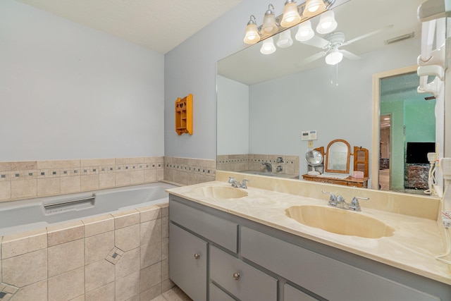 bathroom featuring vanity, tiled bath, a textured ceiling, and ceiling fan