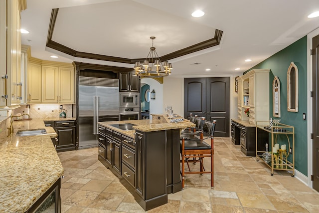 kitchen with built in appliances, crown molding, dark brown cabinetry, and a raised ceiling