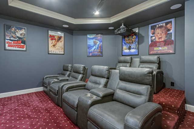 home theater room with a tray ceiling, ornamental molding, and carpet