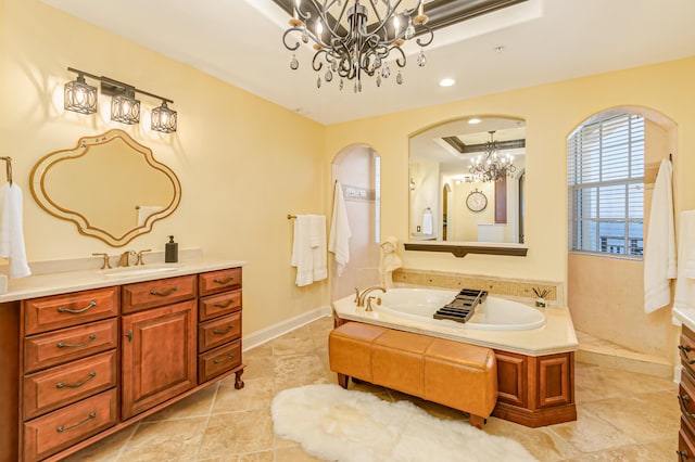 bathroom with vanity, a tray ceiling, a tub, and a chandelier