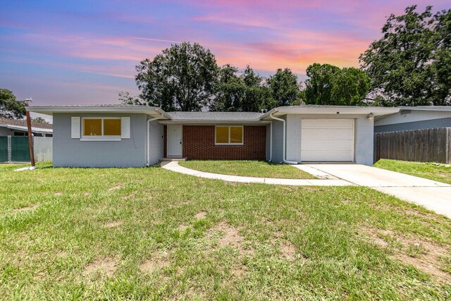 single story home with a garage and a lawn