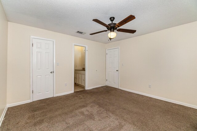 unfurnished bedroom featuring light colored carpet, ensuite bathroom, a textured ceiling, and ceiling fan