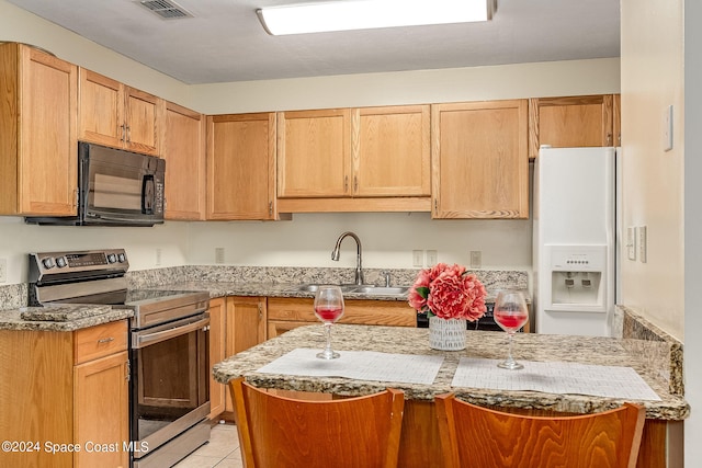 kitchen featuring sink, light stone countertops, white refrigerator with ice dispenser, light tile patterned floors, and stainless steel electric range oven